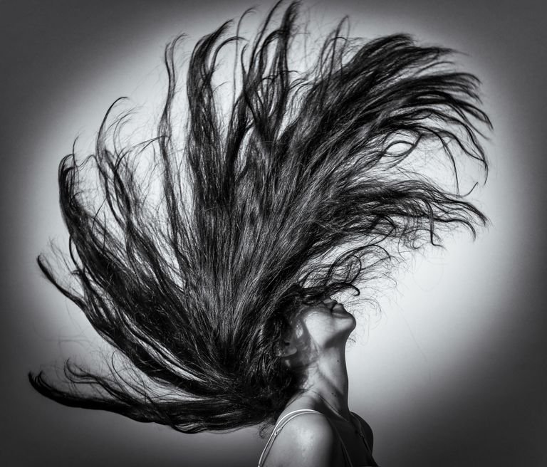 Black and white portrait of a woman flipping her hair dramatically.